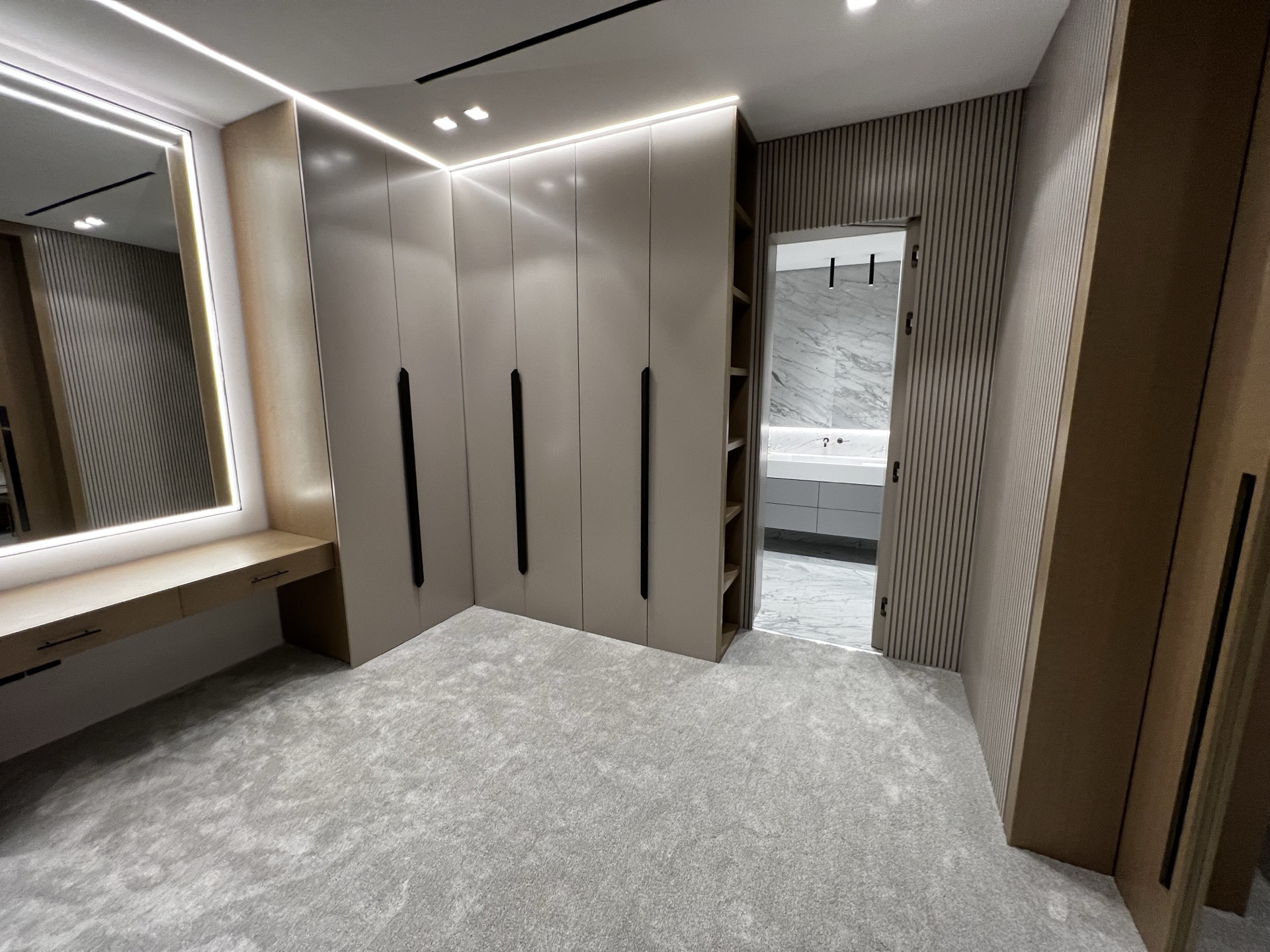 Bespoke dressing room with lit mirror and fluted timber joinery in a Riyadh villa by Dar Anan